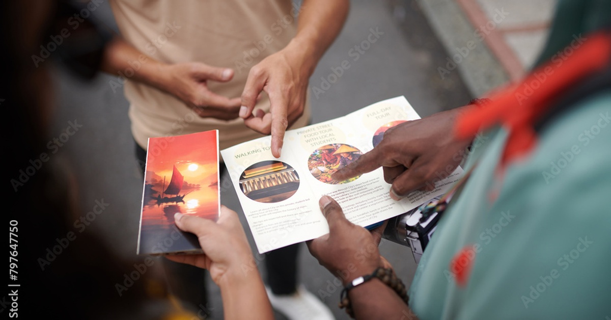 A close-up of hands pointing at a travel brochure with excursions and famous sights displayed on the front.