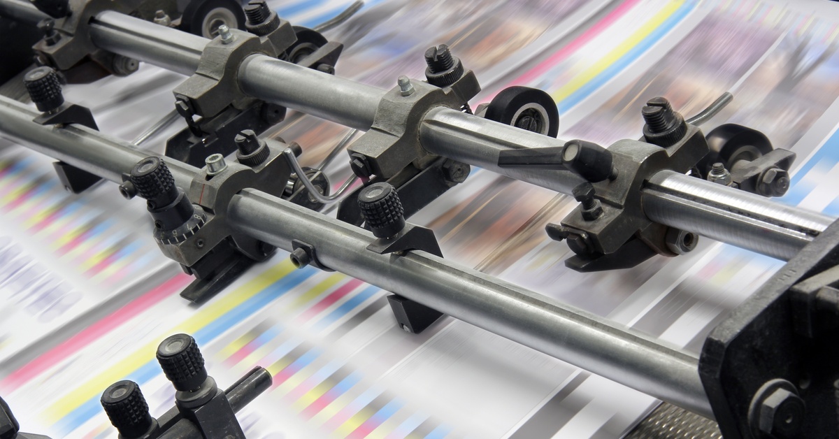 Printing press rollers guide fast-moving color test sheets through a commercial offset printing machine.
